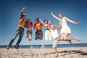 Six teenage boys and girls (16-18) jumping on beach, smiling, portrait